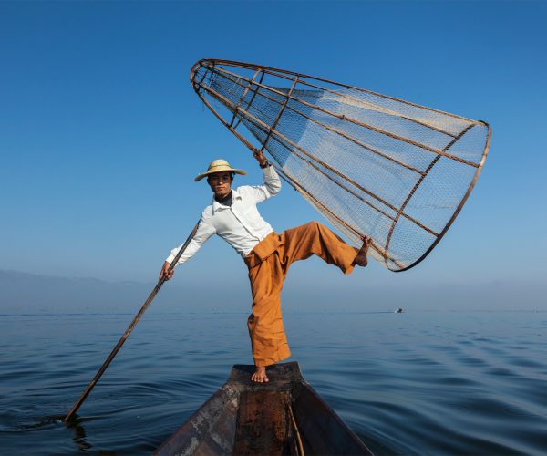 Myanmar travel attraction landmark - Traditional Burmese fisherman with fishing net at Inle lake in Myanmar famous for their distinctive one legged rowing style